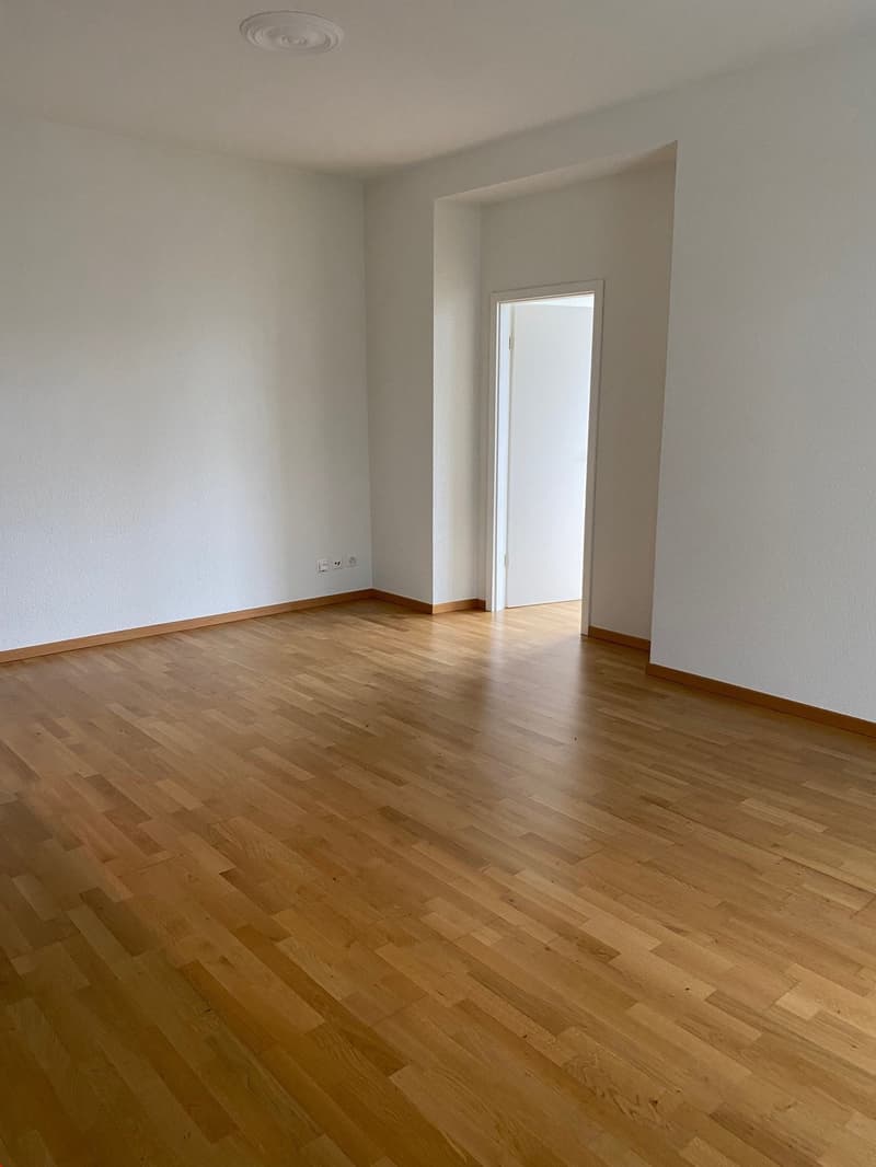 Grosszügiges Wohnzimmer neben offener Küche und Blick in Richtung Schlafzimmer