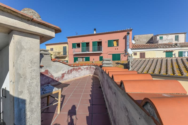 Colorful Mediterranean-style buildings with balconies, tiled roofs, and a walkway leading between the structures