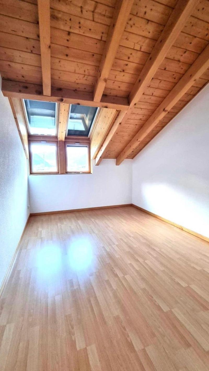 Attic or loft space with wooden beamed ceiling, white walls, and hardwood flooring. The room has two skylights providing natural light.