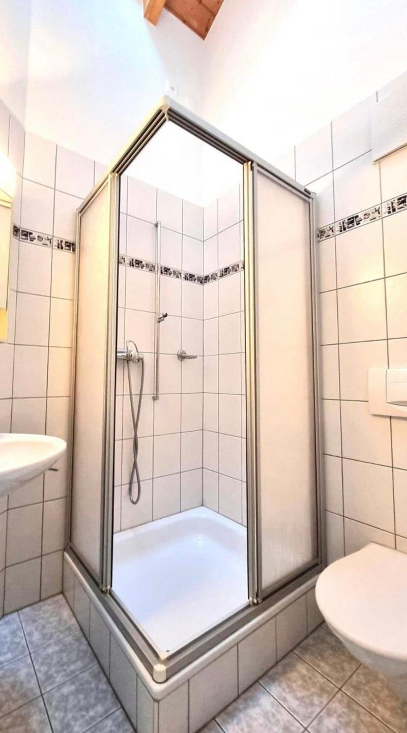 Tiled bathroom with a glass shower enclosure, toilet, and sink.