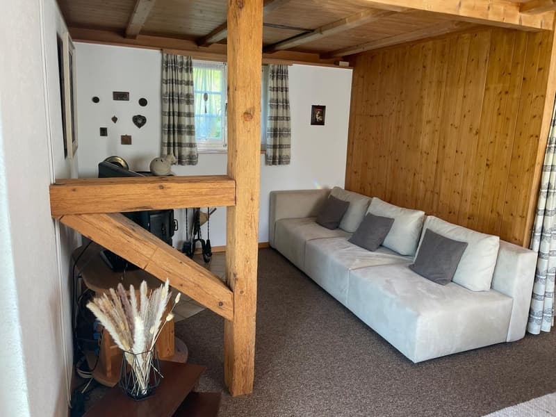wooden walls, wooden pillars, couch, floor, windows, curtains, picture frames, fireplace
