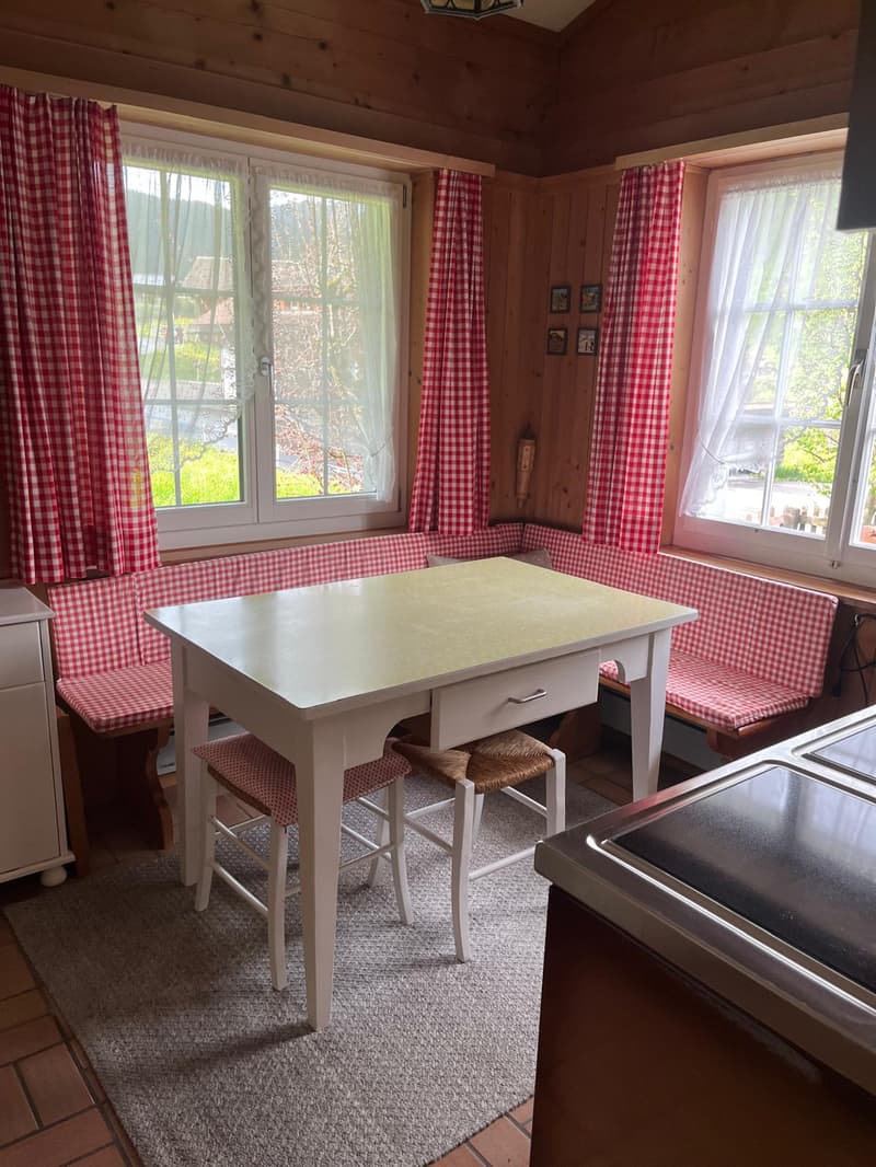 white table and red-white bench seating, tiled floor, double windows, open-plan kitchen