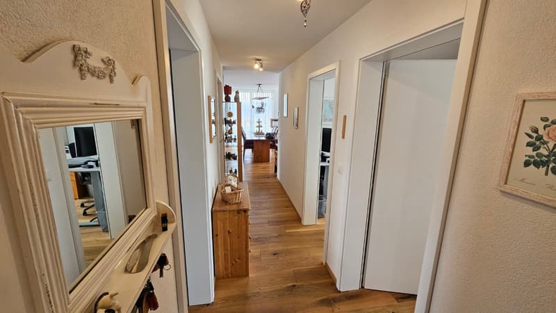 wooden floor, white walls, mirror, wooden cabinet, hallway leading to rooms