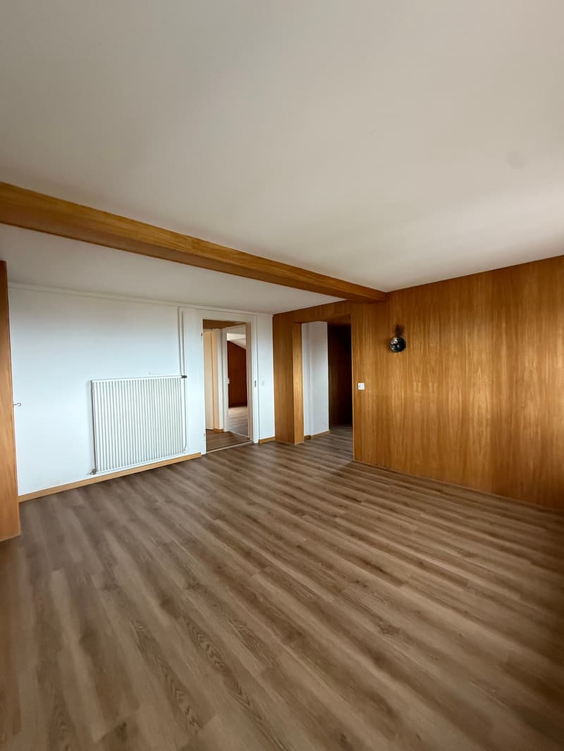empty room, wooden floor, white walls, wooden beams, radiator, open door