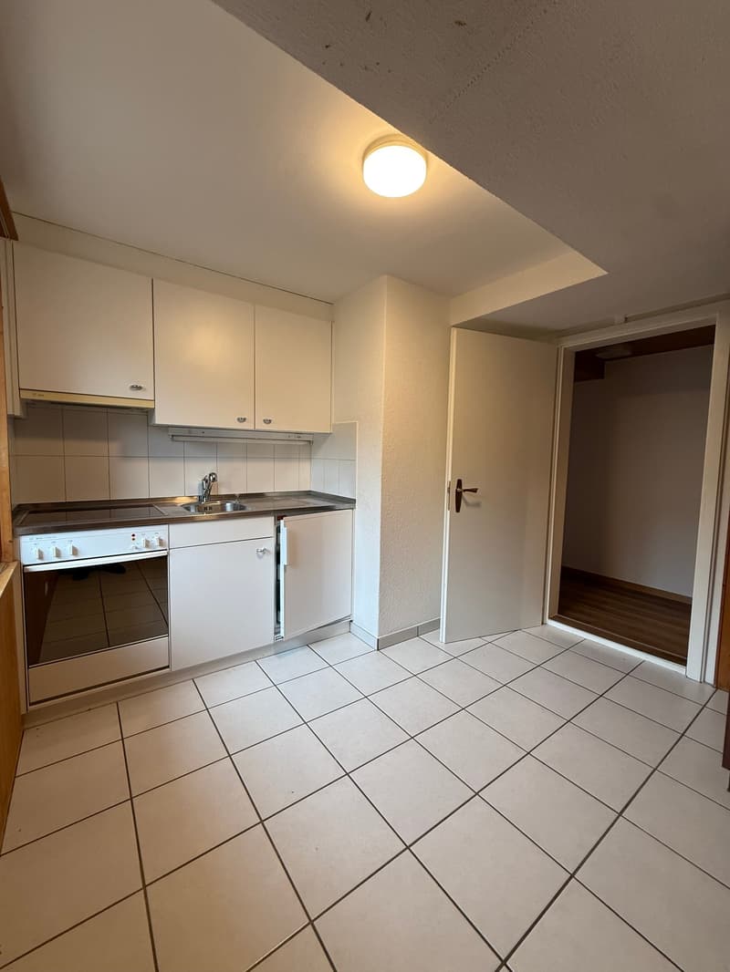 modern kitchen with white cabinets, tiled floor, sink, oven, and a door leading to a closet
