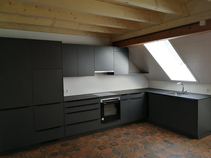 Modern kitchen with black cabinets, granite countertops, and a built-in oven.