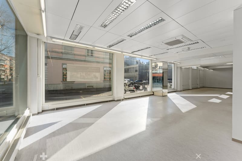 Empty room with large windows, white walls, white ceiling, white floor, and visible ceiling lights