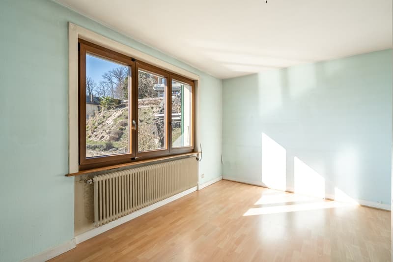 Empty room with hardwood floors, wooden window, radiator, blue walls