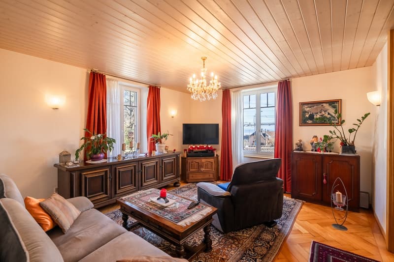 Chandelier, sofa, TV, coffee table, armchair, wooden cabinets, windows with red curtains