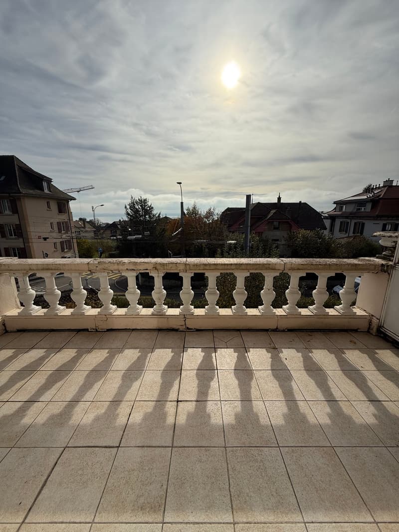Outdoor balcony with a tiled floor, a white railing, and a city view.