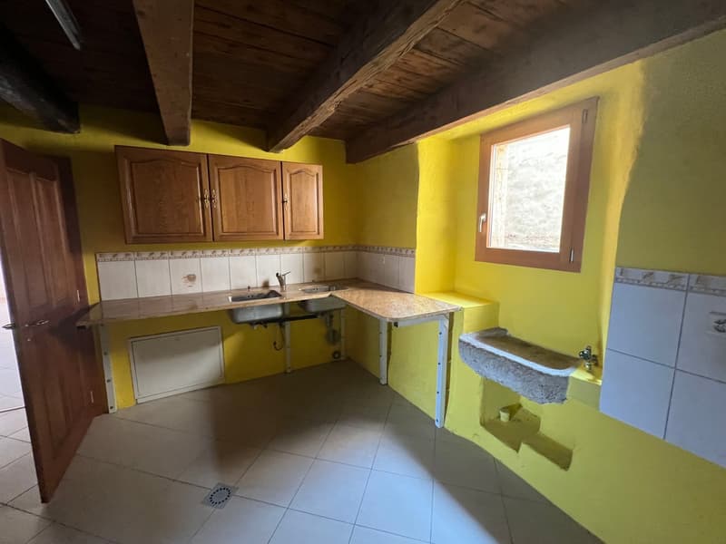 Rustic kitchen with wooden cabinets, yellow walls, tile flooring, and a private washing machine