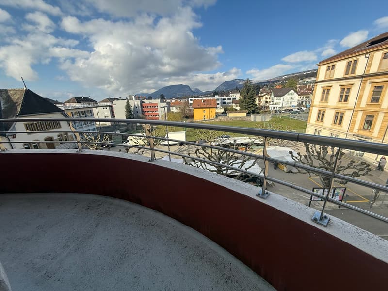 Balcony with metal railings, concrete floor, view of the city and mountains
