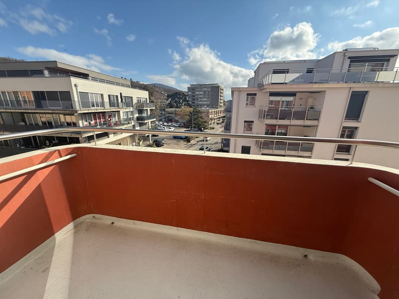 Balcony with metal railing, red wall, view of the street and buildings