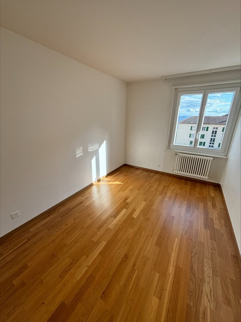 empty room, wooden floor, white walls, large window, white radiator