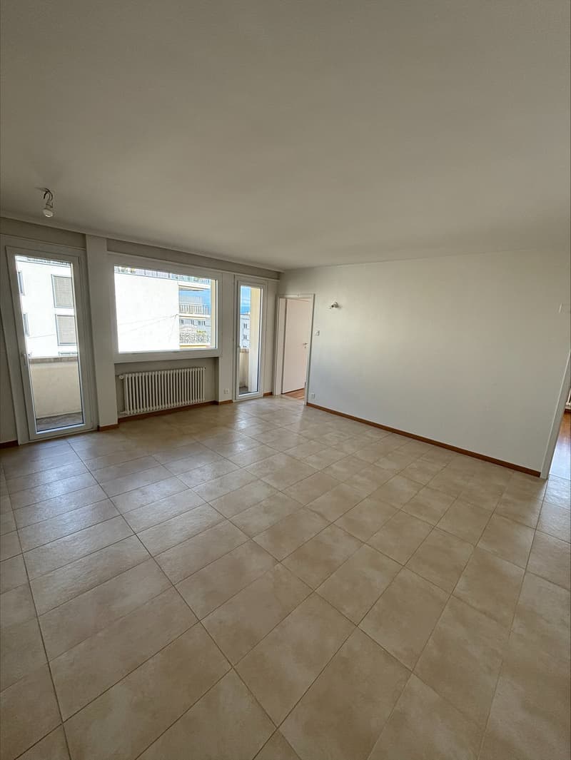 empty room, white walls, tiled floor, large windows, balcony, radiator