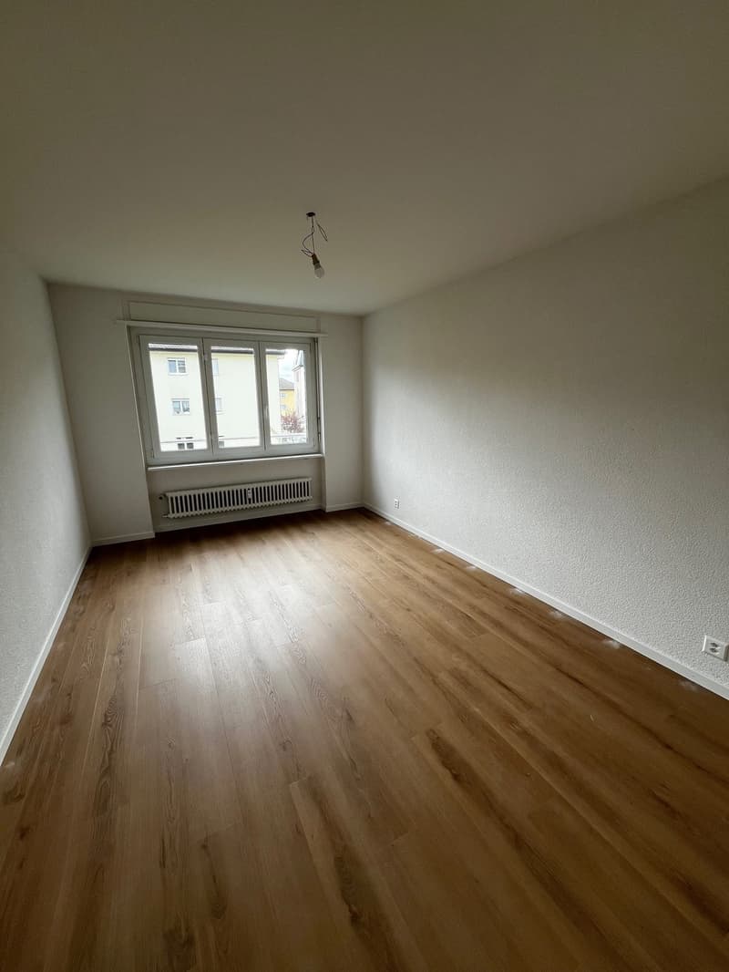 empty room, wooden floor, white walls, large window, white radiator