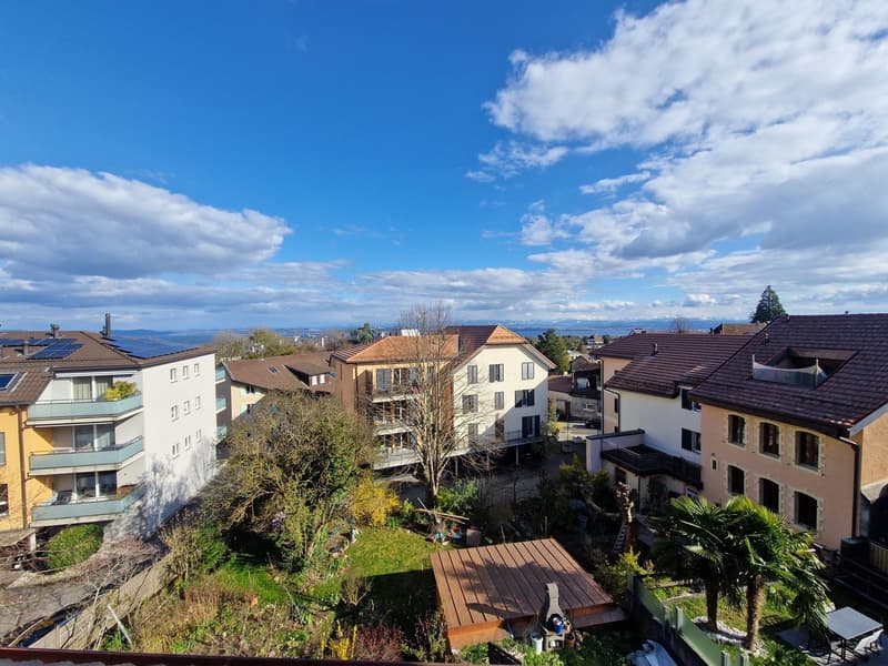 Aerial view of a residential area with multiple buildings, solar panels, and a garden.