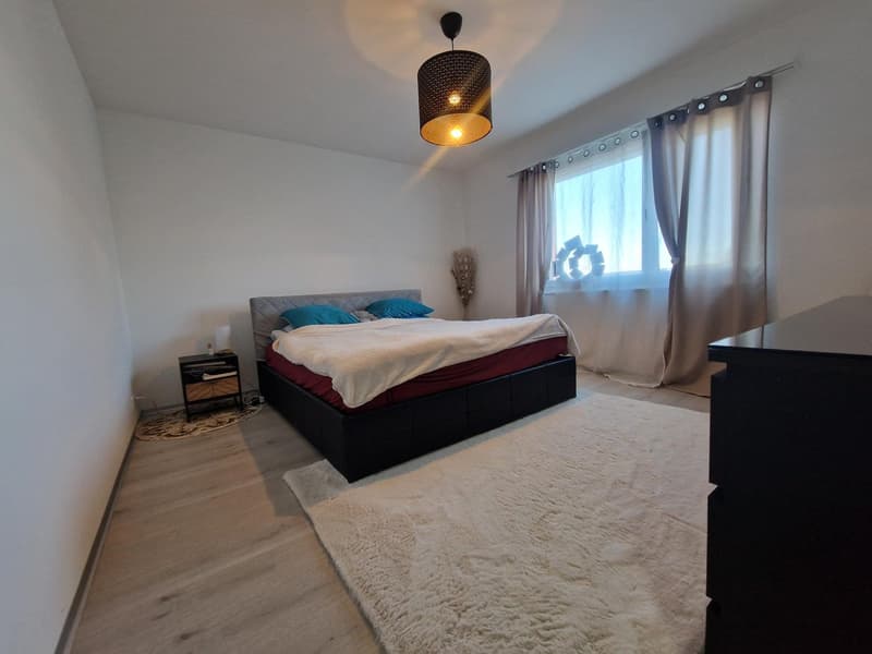 Bedroom with bed, nightstand, rug, and window with curtains
