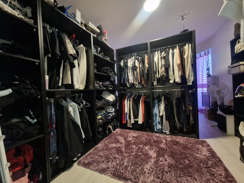 walk-in closet with clothes, shoes, and accessories on shelves and hangers, pink carpet