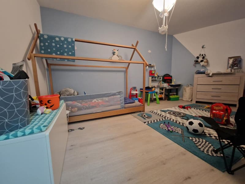 Children's room with wooden bed, toys, rug, chair, and storage boxes