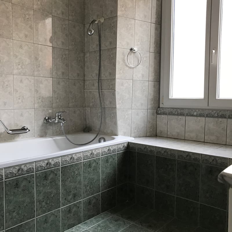 Bathroom with bathtub, shower head, faucet, window, tiled walls, tiled floor