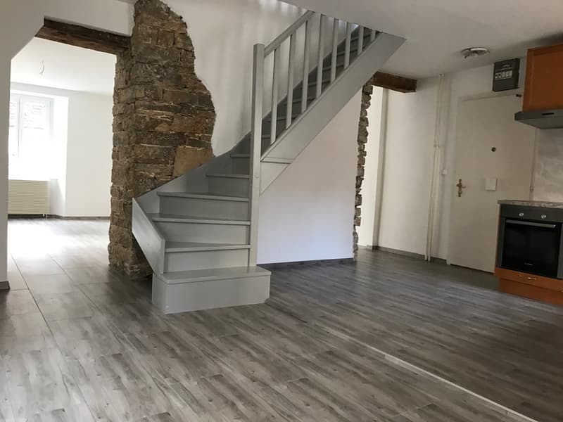 empty room, wooden floor, stone pillar, staircase, white walls, kitchen area