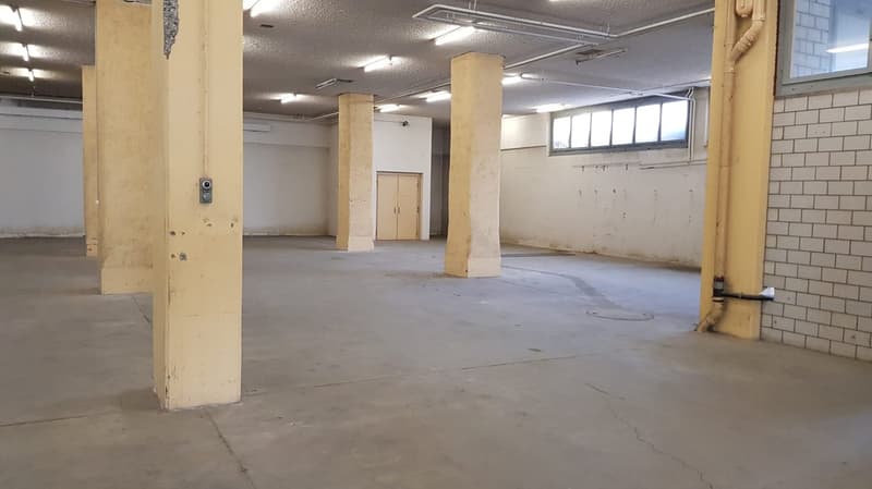 large room, concrete floor, industrial design, beams, no windows, white walls