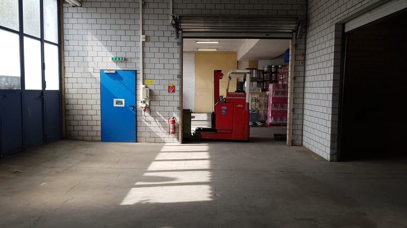 Warehouse, concrete floor, white tiled walls, open door, forklift in the doorway, fire extinguisher