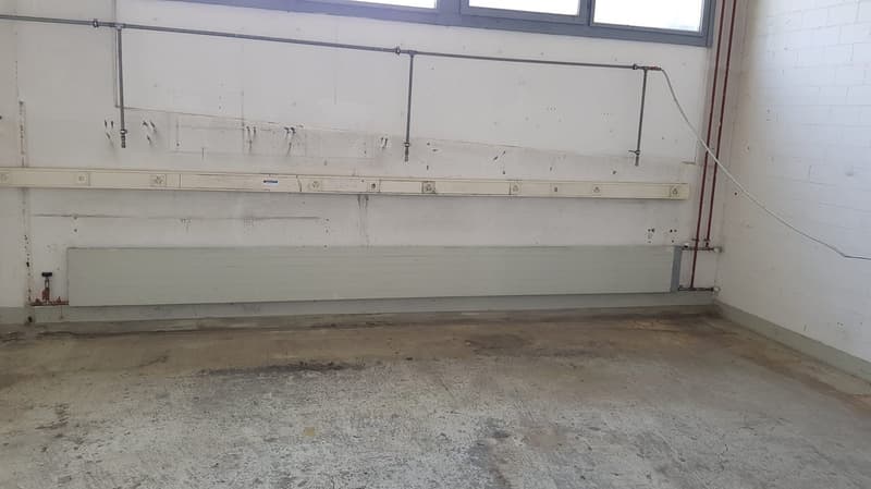 Empty room with concrete floor, mounted pipe and electrical outlets