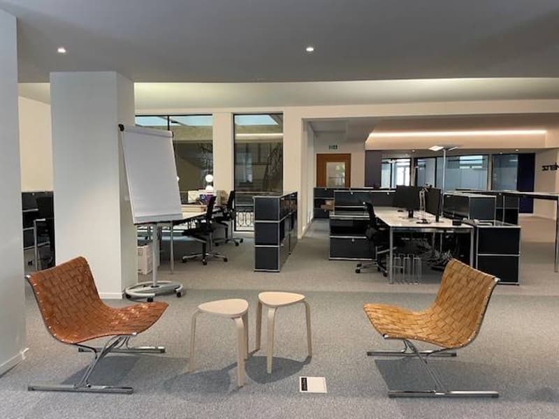 Open space office with desks, chairs, whiteboard, and natural light.