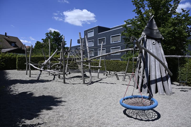 Playground with wooden structures, swings, and a rope ladder.