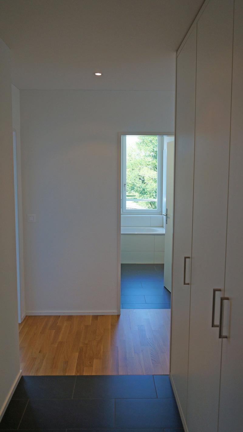 Empty room, wooden floor, white walls, large window, bathtub, white cabinets