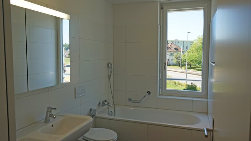 Bathroom with bathtub, sink, toilet, mirror, and window