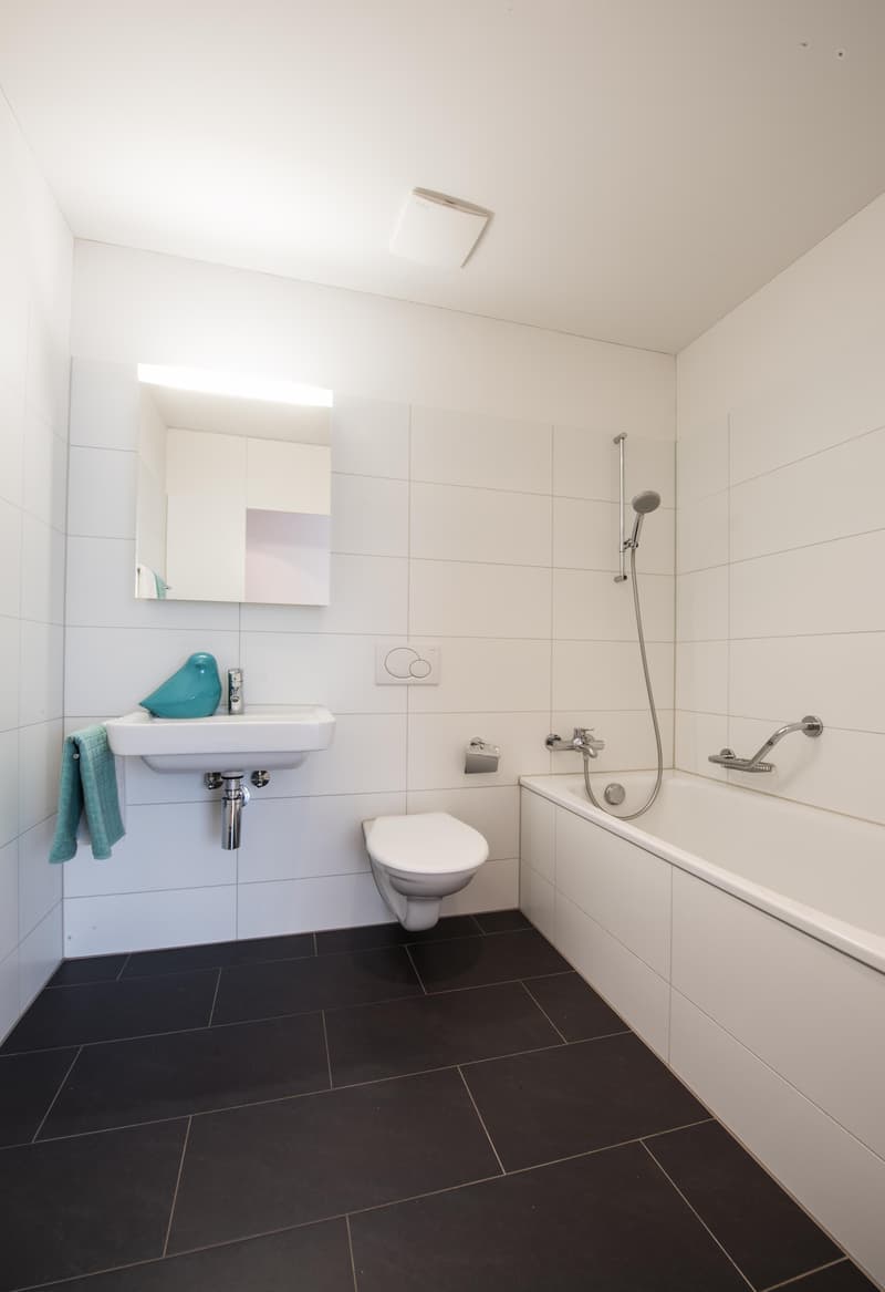 white tiles, white bathtub, white sink, white toilet, mirror, towel, shower head