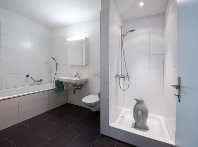 modern bathroom with white tiles, bathtub, toilet, sink, shower, mirror, towel rack