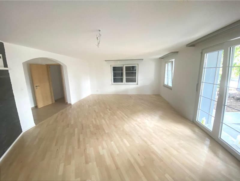 large room, wooden floors, glass sliding doors, white walls, ceiling light, windows