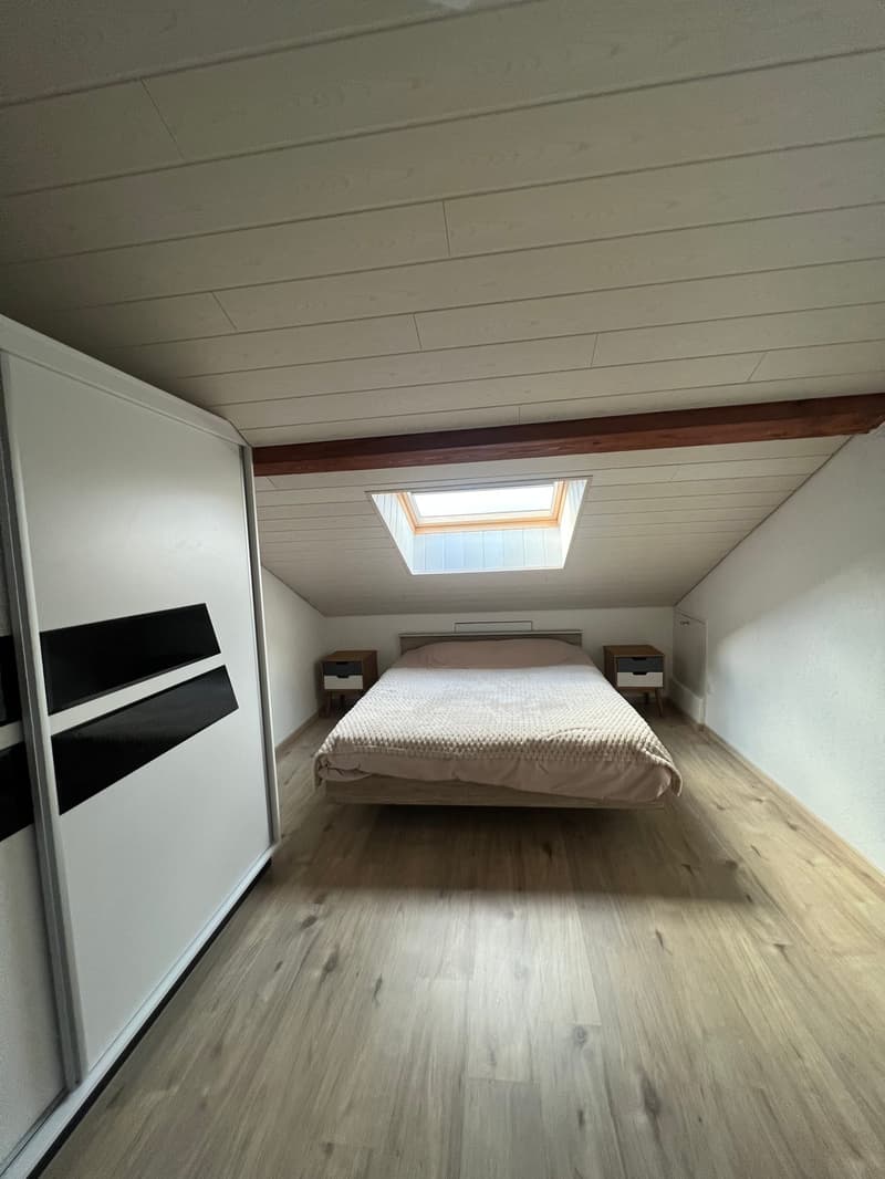 A room with white ceiling, wooden floor, a bed with two nightstands, and a wardrobe