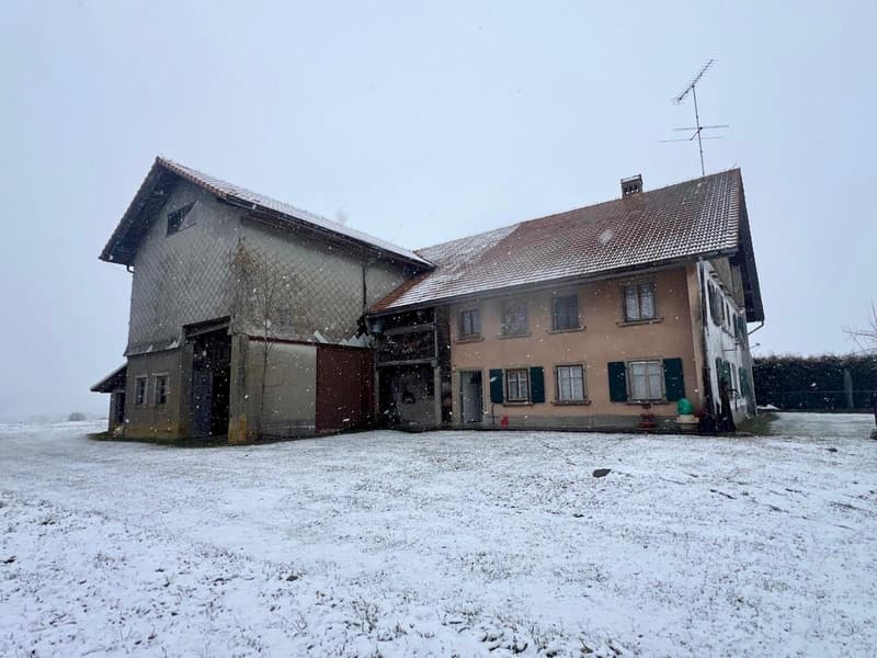 2 story house, grey facade, brown roof, large garage, surrounded by snow.