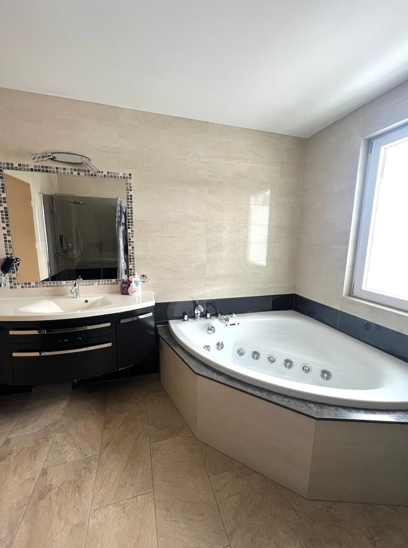 large bathtub, sink, mirror, window, tiled floor