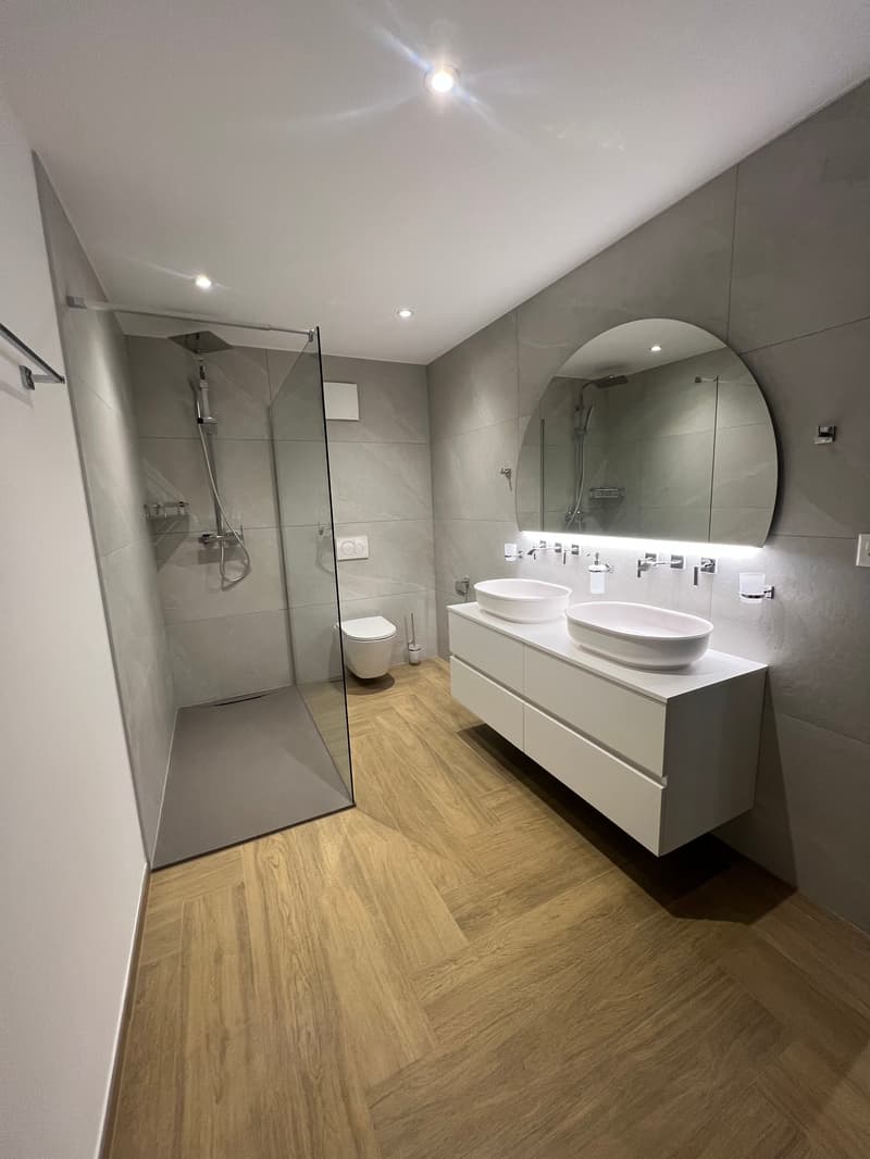 modern bathroom with walk-in shower, double sink, mirror, toilet, wooden floor