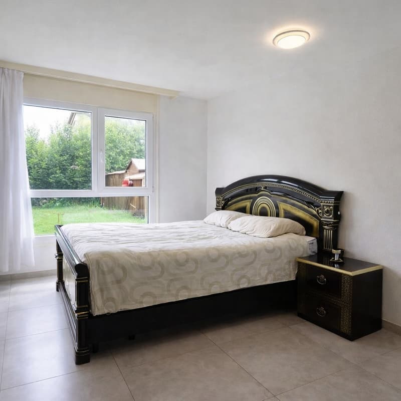 Bedroom with a double bed, nightstand, large window with white curtains, tiled floor, and a view of a grassy yard