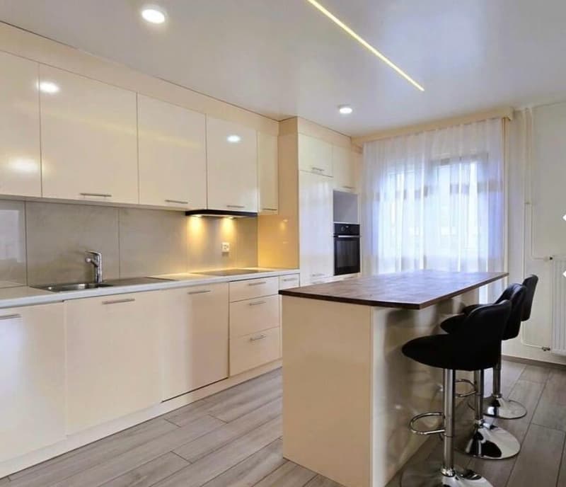 modern kitchen with white cabinets, wooden countertop, black stools, stainless steel sink, dishwasher, washing machine, oven, windows with white curtains