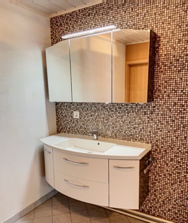 Bathroom with white vanity, mirror, and tiled wall