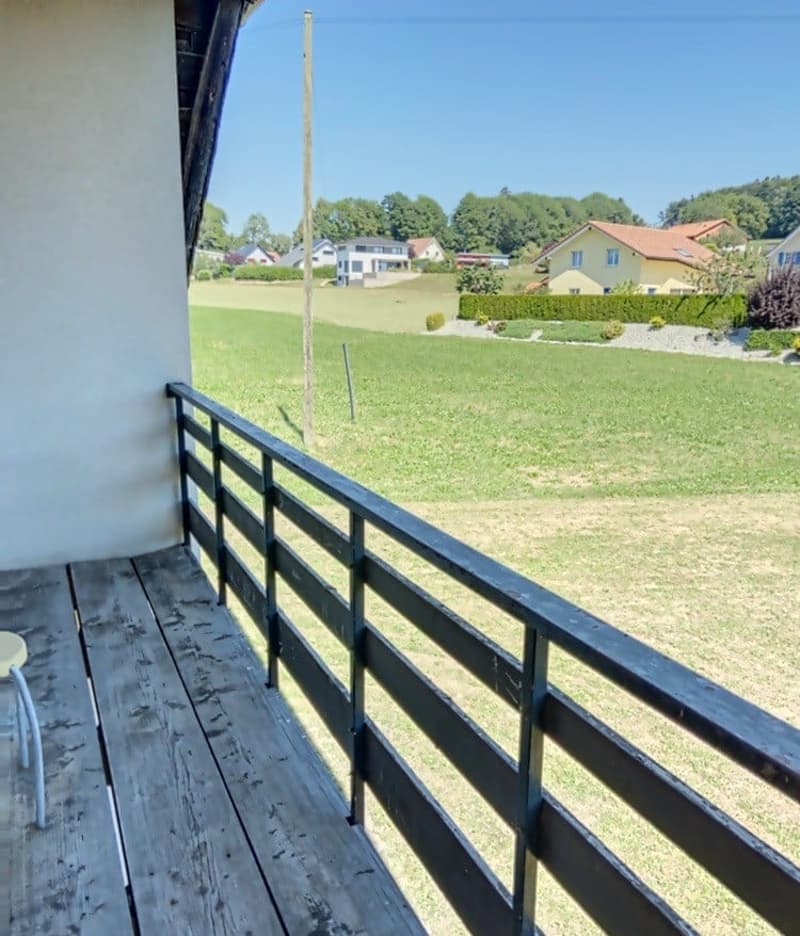 wooden floor, black railing, view of a grassy field