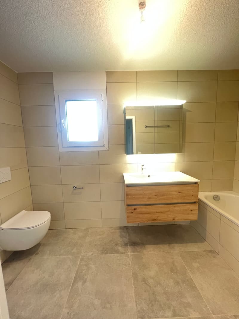 Bathroom with white tiles, wooden cabinet, white sink, mirror, bathtub, toilet, window