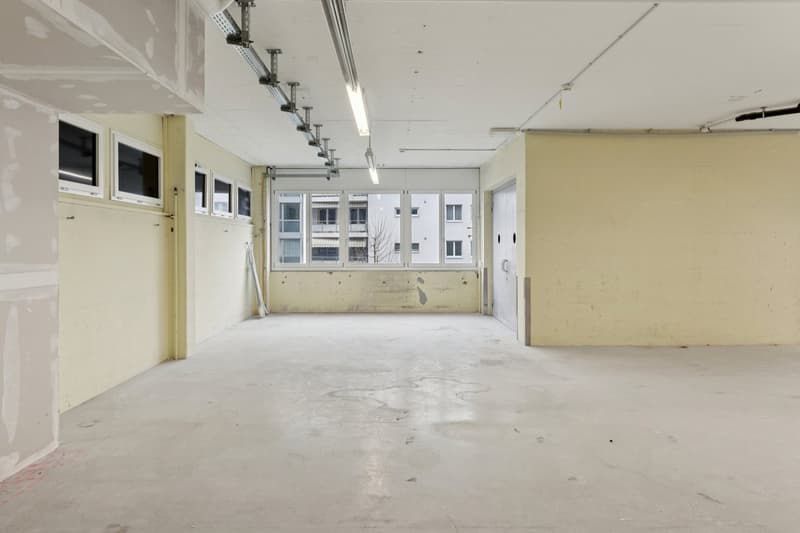 Empty room, exposed pipes on the ceiling, windows, entrance door, unfinished walls, clean floor