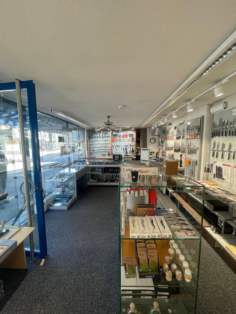 Store interior with glass walls, ceiling fans, display cases, and various products on shelves.