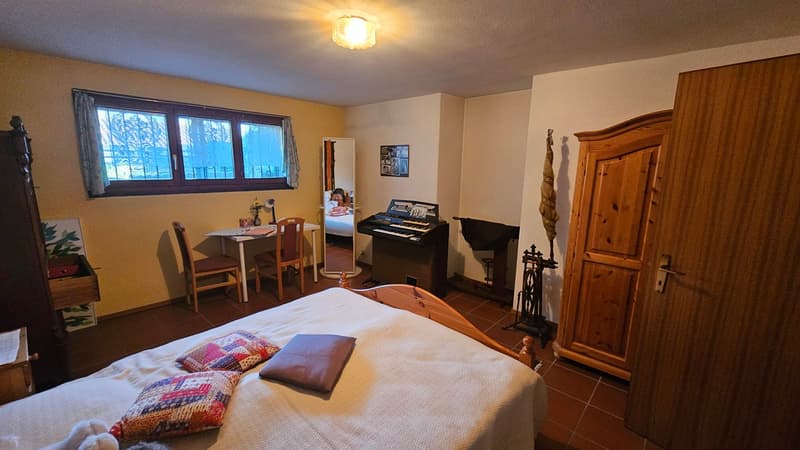 Bedroom with bed, desk, chairs, piano, cabinet, window, and decorative items