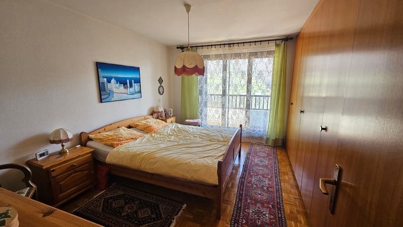 Bedroom with bed, nightstands, lamp, rug, wardrobe, painting, balcony with curtains