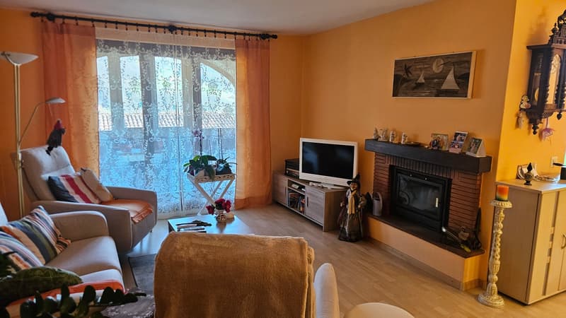 Fireplace, TV, couch, armchair, coffee table, floor lamp, window with curtains